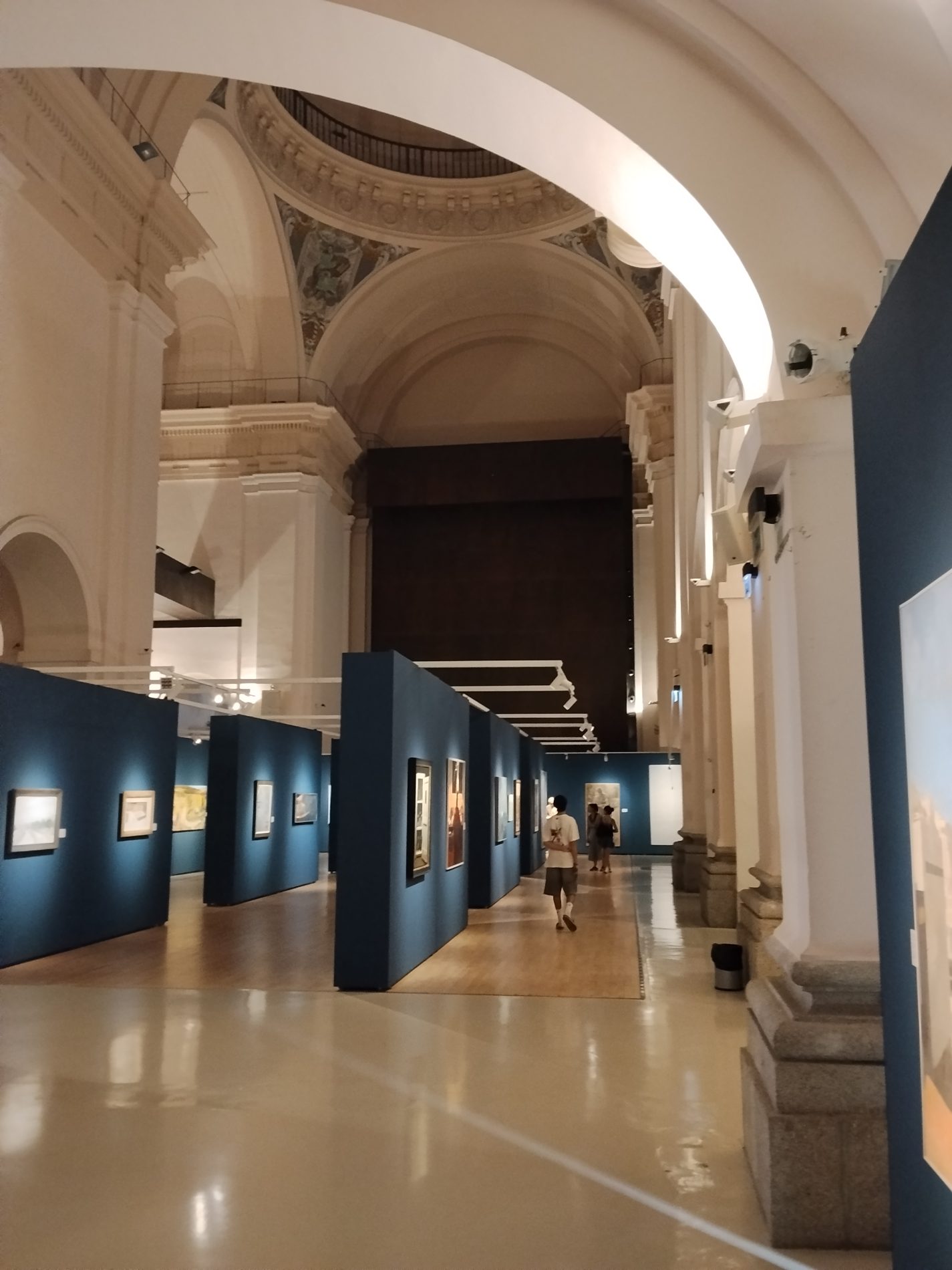 Galería de un museo con visitantes recorriendo grandes obras de arte.